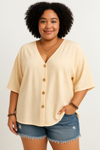 Plus size model in a casual light beige apricot short sleeve V-neck blouse with button front, styled with distressed denim shorts featuring frayed hem